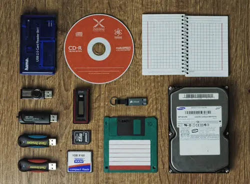 Wir retten Ihre Daten, auch von defekten Speichermedien. Tisch mit diversen Speichermedien, wie CD, Festplatte, Diskette, USB Sticks, Notizbuch